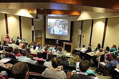 布鲁克斯米. O ' brien礼堂 full of participants watching presenter. Image of people on screen at front of room.